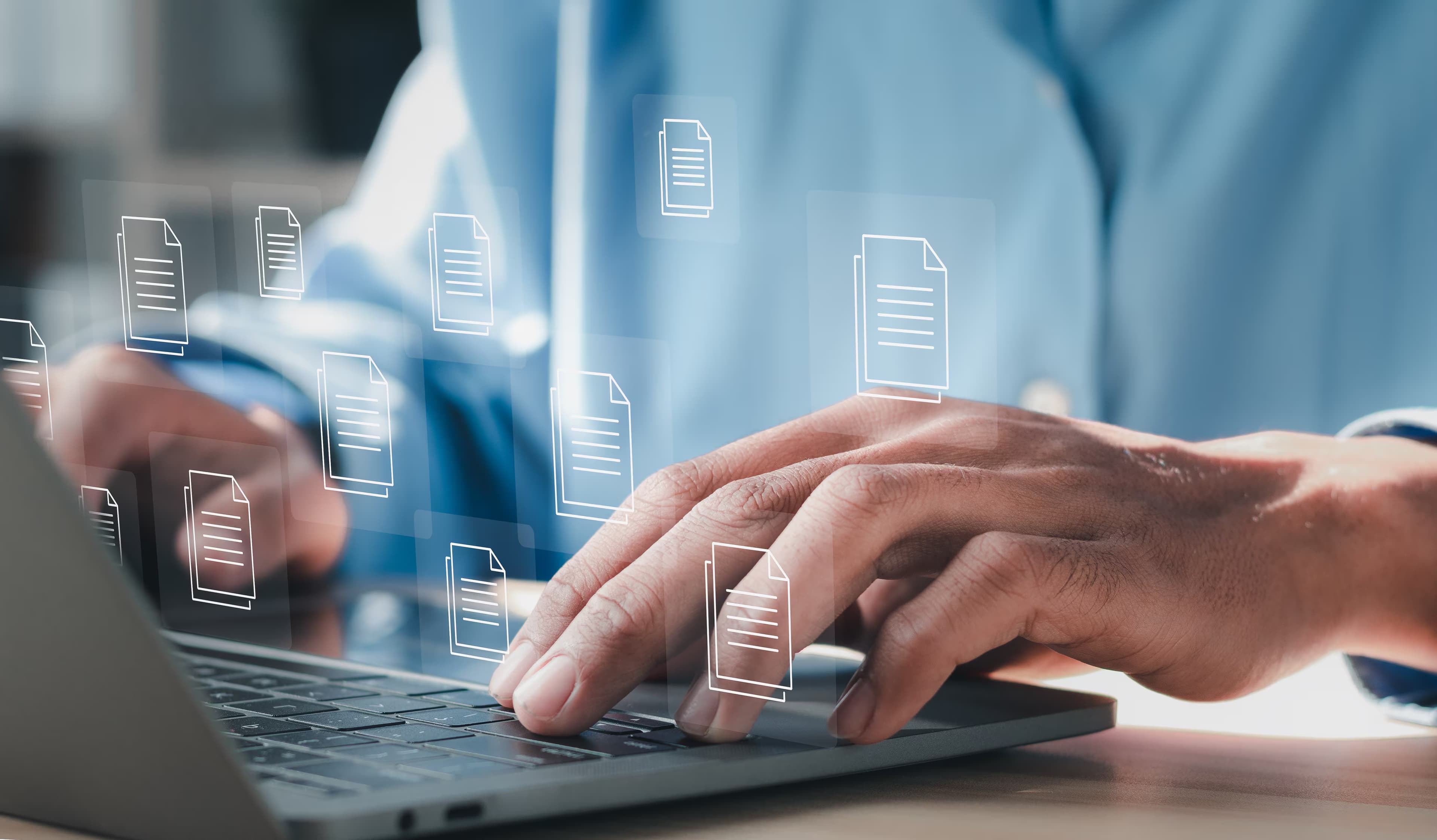 Hands typing on a laptop with document icons surfacing from a knowledge library