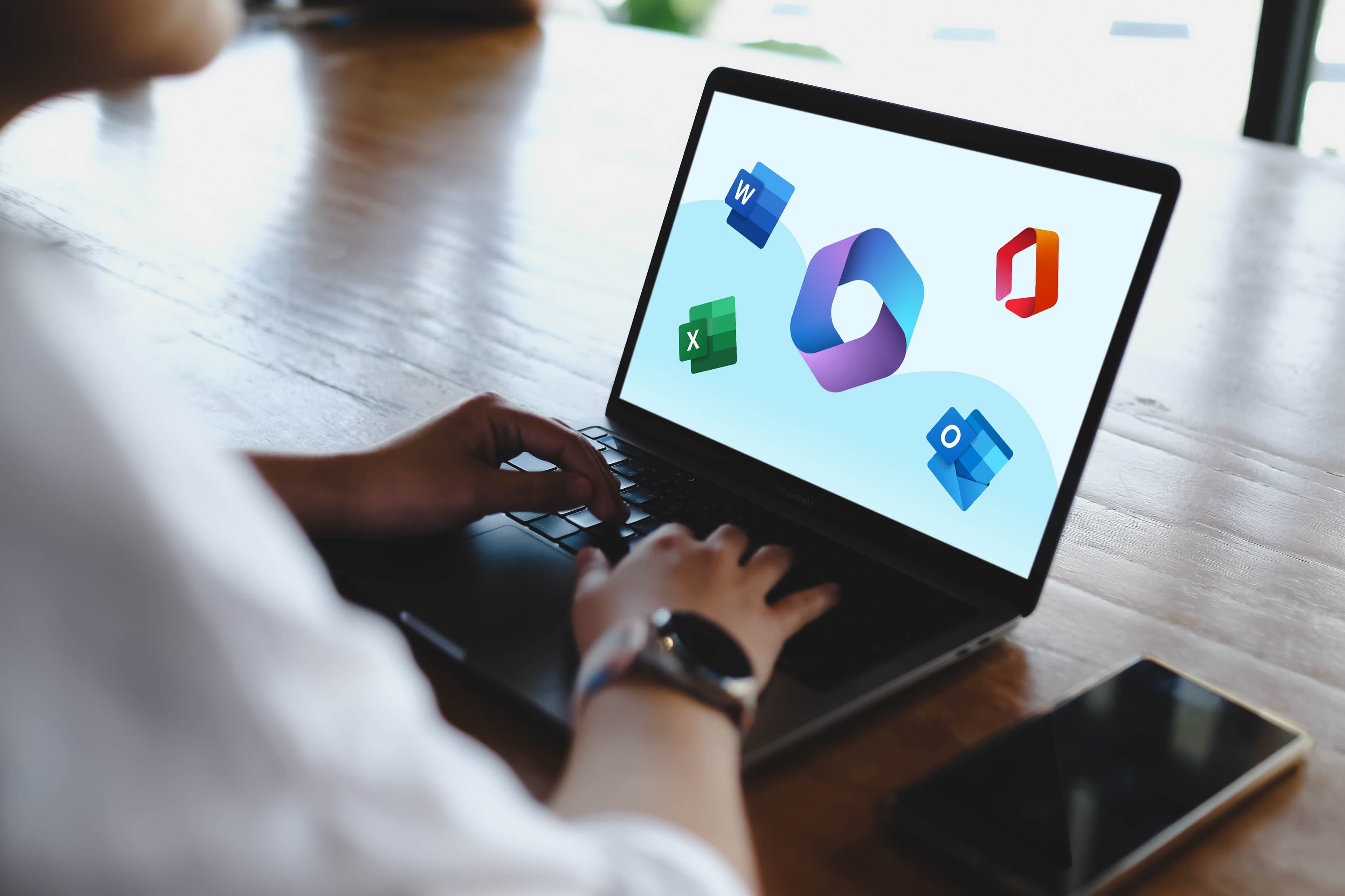 Person working on a laptop showing Microsoft 365 applications