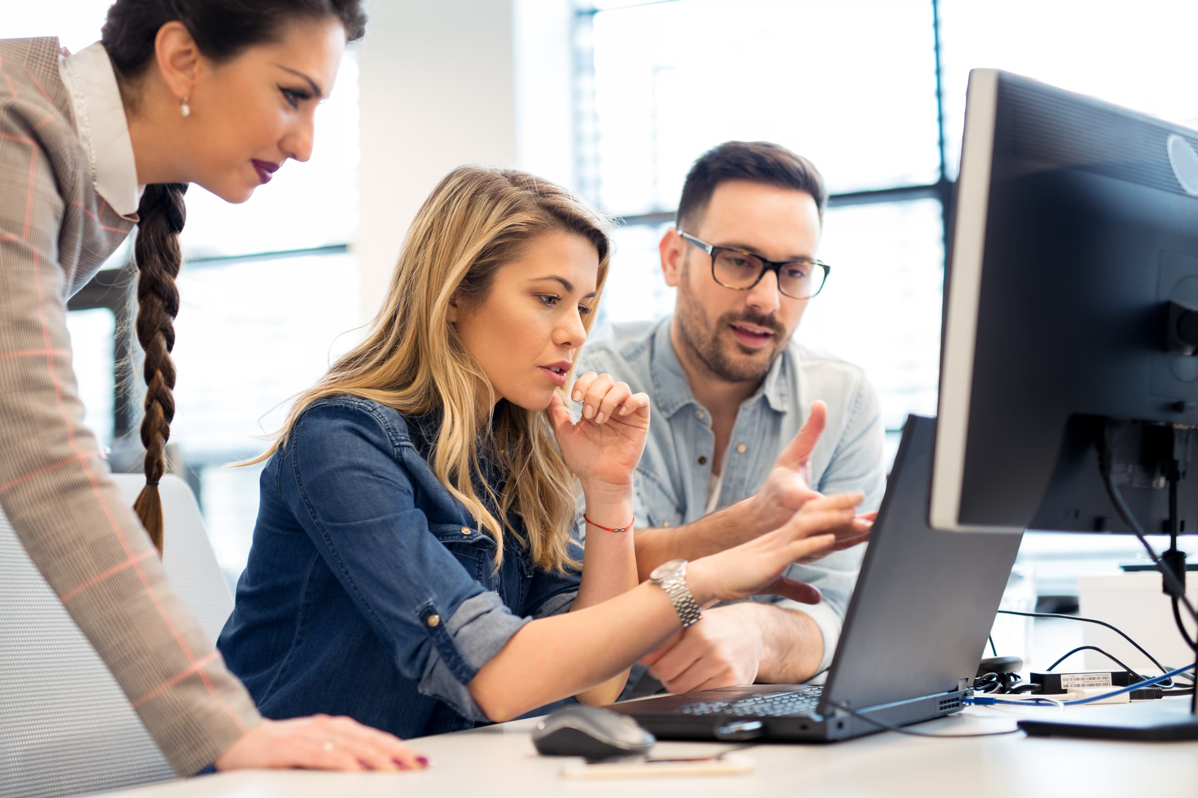 Three colleagues reviewing an upgrade plan together at a workstation