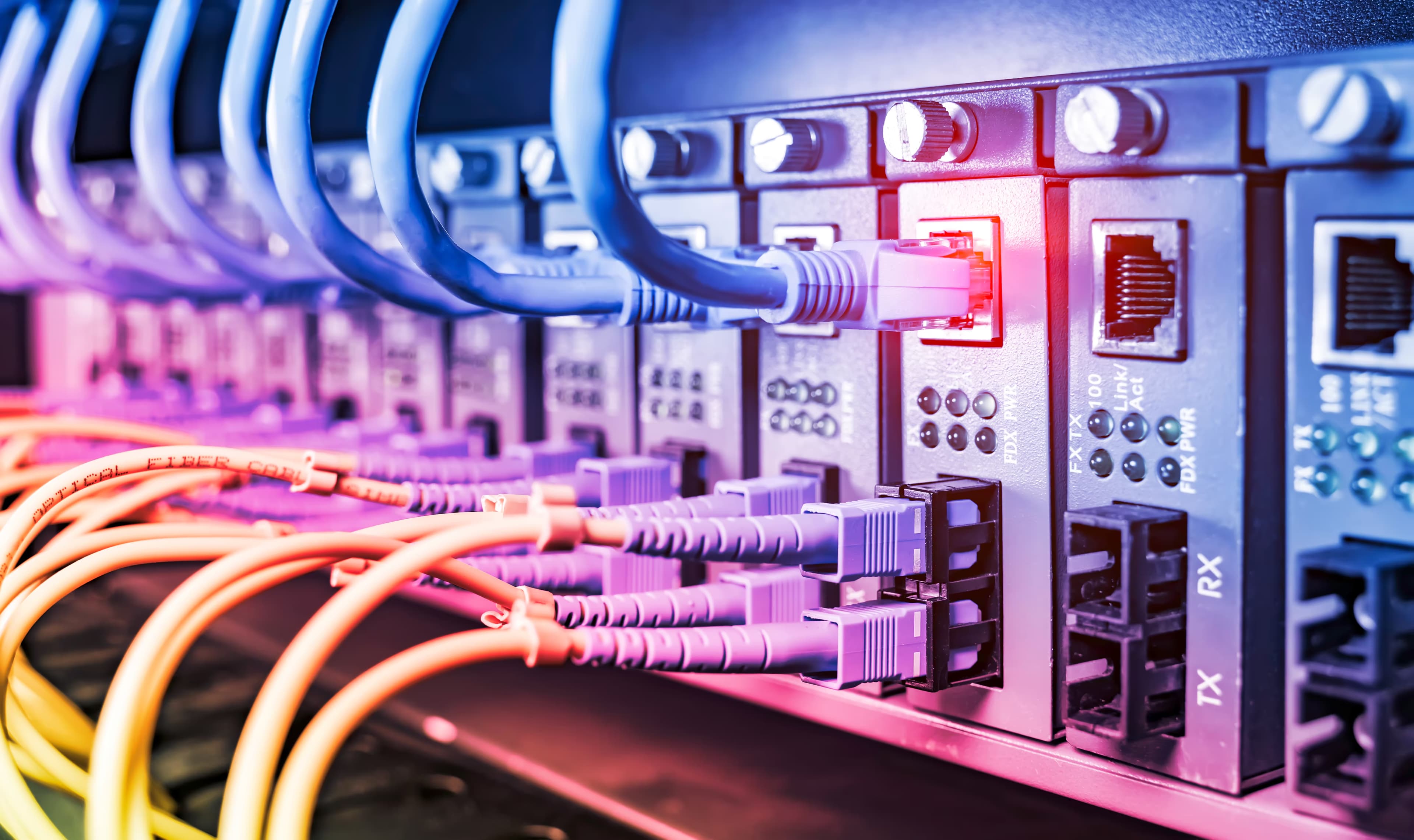 Ethernet and fiber cables plugged into network switch ports with status LEDs